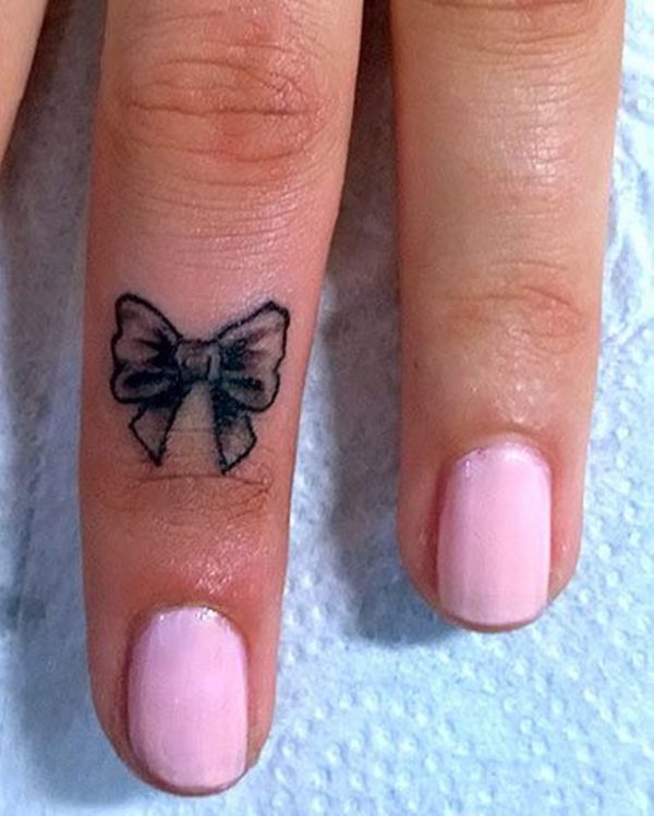 Small Bow Tattoo On Middle Finger