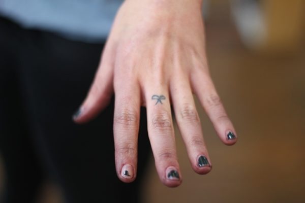 Tiny Bow Tattoo On Middle Finger